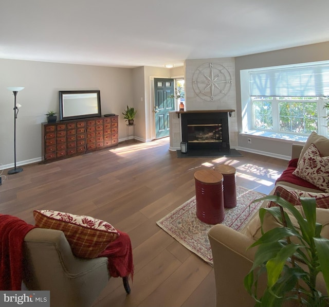 living room featuring wood finished floors, a tile fireplace, and baseboards