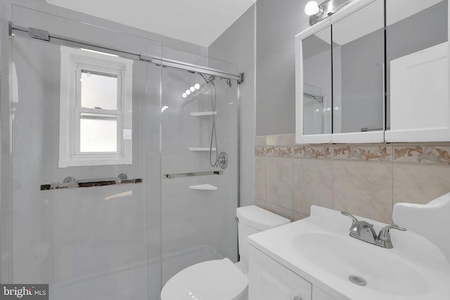 bathroom with walk in shower, vanity, toilet, and tile walls