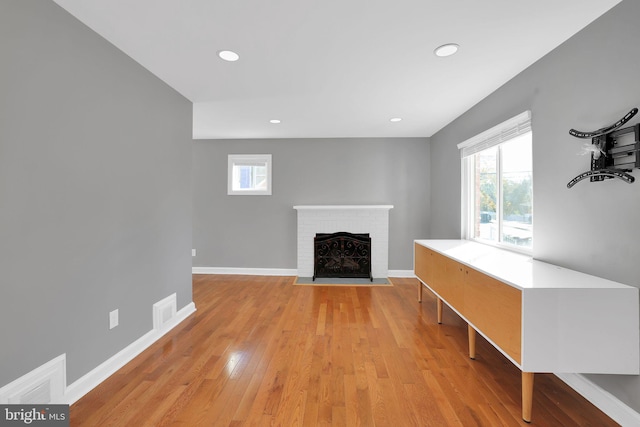 living room featuring a brick fireplace and light hardwood / wood-style floors