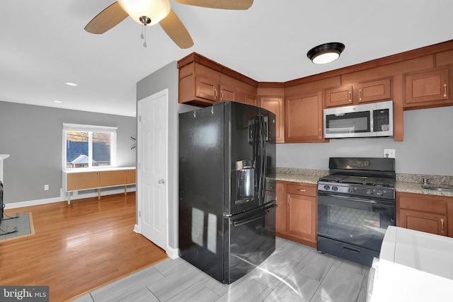 kitchen with light hardwood / wood-style flooring, black appliances, ceiling fan, and light stone countertops