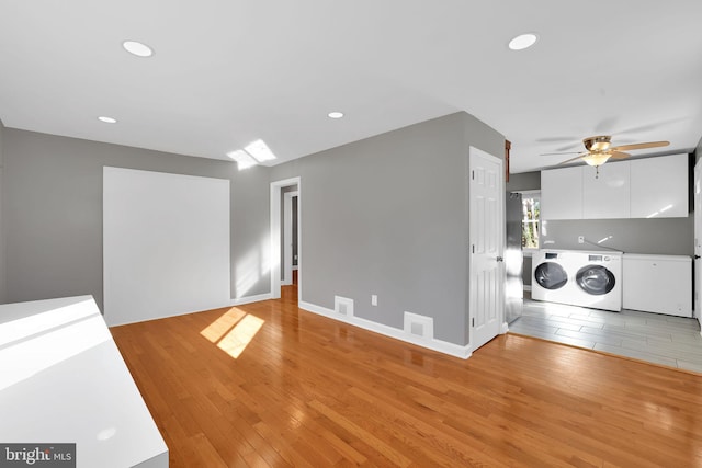 laundry room with ceiling fan, washer and dryer, and light hardwood / wood-style flooring