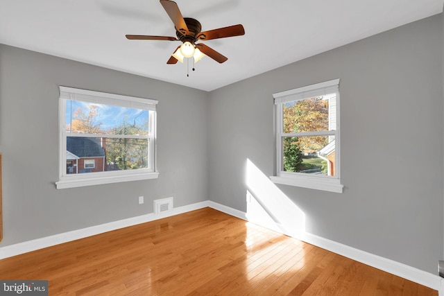 unfurnished room with ceiling fan, wood-type flooring, and a healthy amount of sunlight