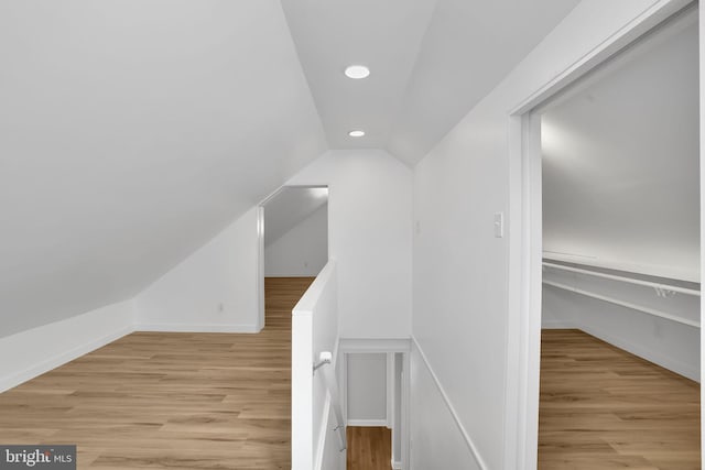 additional living space featuring light wood-type flooring and vaulted ceiling