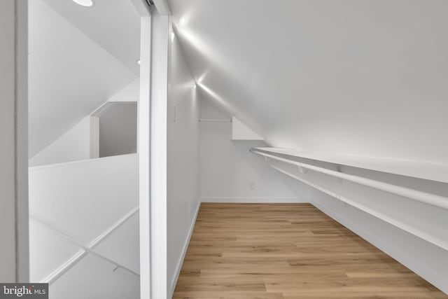 spacious closet with light hardwood / wood-style flooring and lofted ceiling