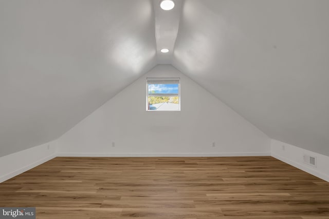 additional living space with wood-type flooring and vaulted ceiling