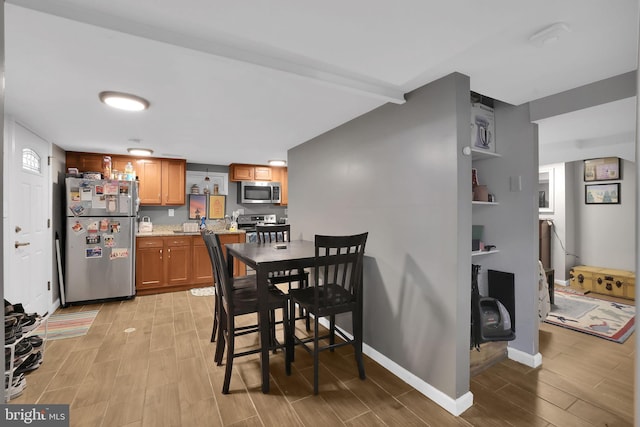 dining room featuring beamed ceiling and light hardwood / wood-style floors