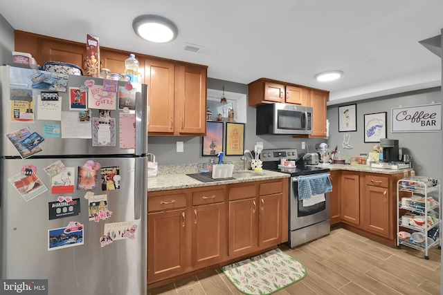 kitchen featuring stainless steel appliances, light hardwood / wood-style floors, and light stone countertops