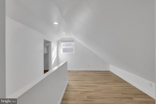 additional living space with light wood-type flooring and lofted ceiling