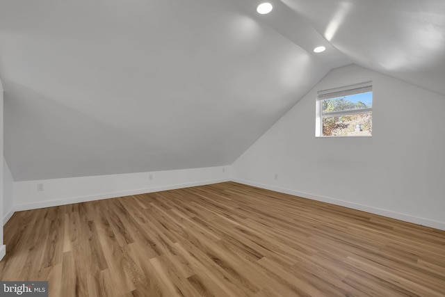 bonus room with light wood-type flooring and vaulted ceiling