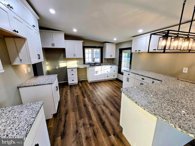 kitchen featuring decorative light fixtures, dark hardwood / wood-style flooring, sink, white cabinets, and lofted ceiling