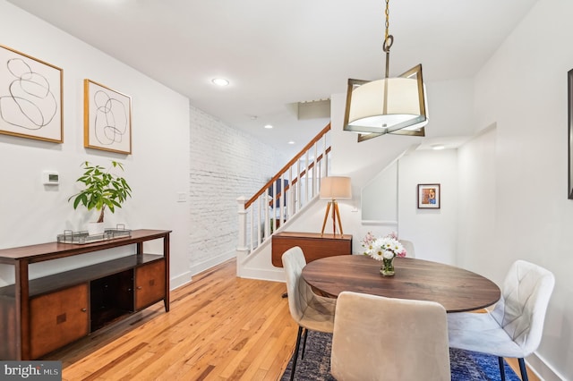 dining room featuring brick wall and light hardwood / wood-style flooring