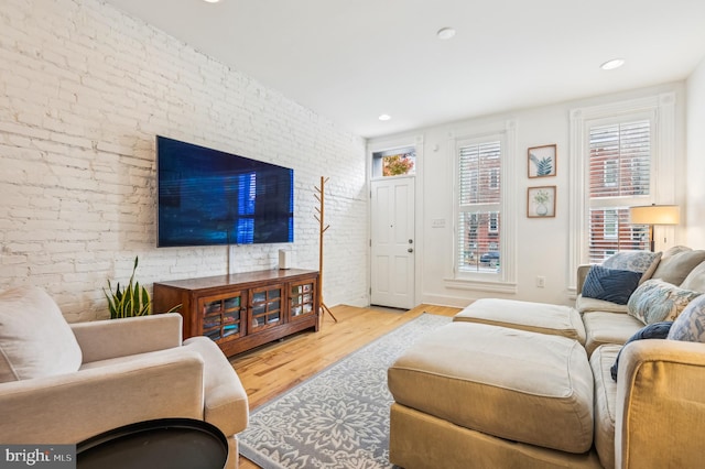 living room featuring light hardwood / wood-style flooring and brick wall