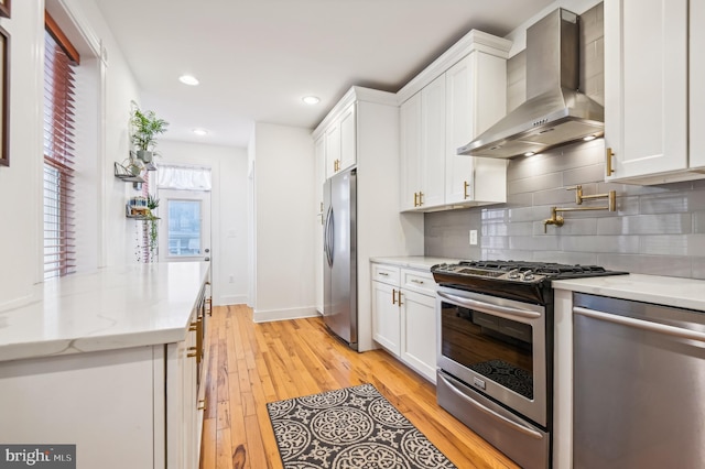 kitchen with white cabinetry, wall chimney range hood, and stainless steel appliances