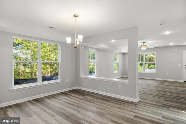 unfurnished room featuring wood-type flooring, ceiling fan with notable chandelier, and plenty of natural light