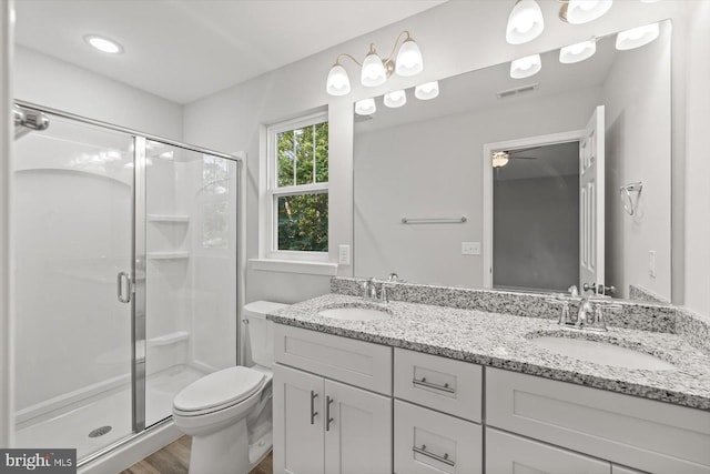 bathroom with hardwood / wood-style floors, vanity, ceiling fan, toilet, and a shower with shower door