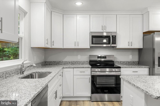 kitchen with white cabinets, sink, light stone countertops, and stainless steel appliances