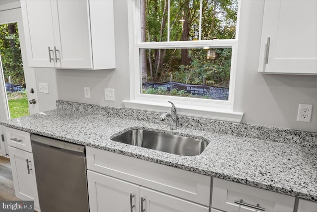 kitchen with stainless steel dishwasher, white cabinetry, and sink