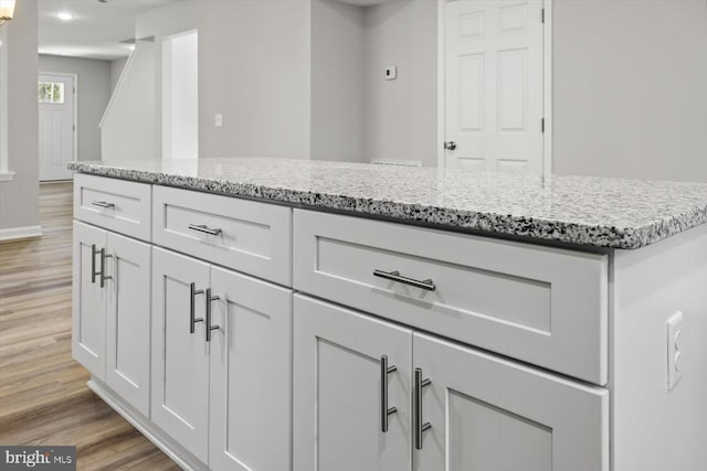 kitchen featuring white cabinetry, light hardwood / wood-style flooring, and light stone counters