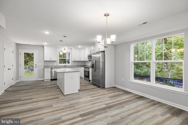 kitchen with pendant lighting, a kitchen island, light hardwood / wood-style floors, and stainless steel appliances