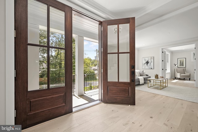 doorway to outside featuring plenty of natural light, light wood-type flooring, and crown molding