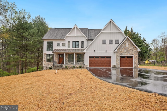 view of front of home featuring a standing seam roof, a porch, board and batten siding, asphalt driveway, and stone siding