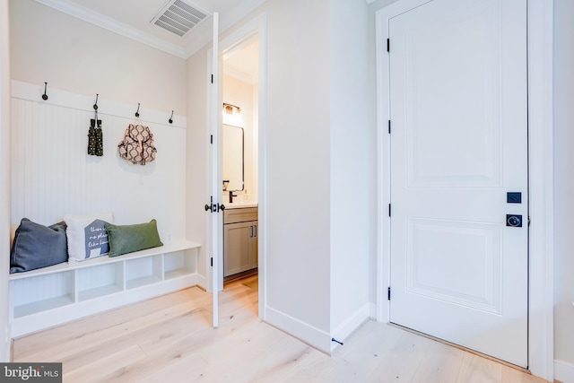 mudroom featuring light wood-style flooring, crown molding, and baseboards