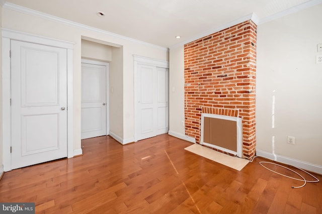 unfurnished living room featuring wood-type flooring and ornamental molding