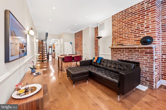 living room with light hardwood / wood-style floors, brick wall, and crown molding