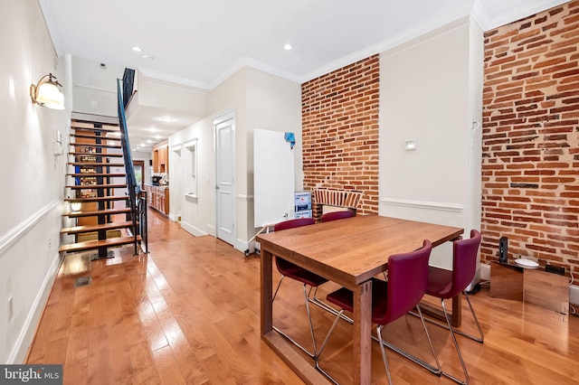 dining room featuring crown molding, light hardwood / wood-style floors, and brick wall