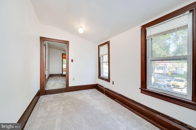 carpeted spare room featuring a baseboard radiator, plenty of natural light, and vaulted ceiling