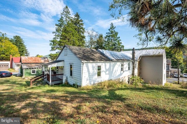 view of side of home featuring a lawn and covered porch