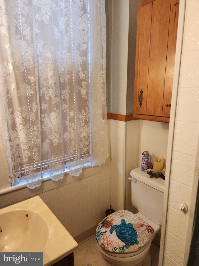 bathroom featuring tile patterned flooring, vanity, toilet, and tile walls