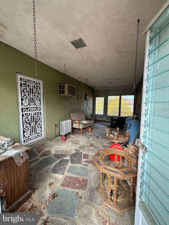 interior space with an AC wall unit, radiator heating unit, and vaulted ceiling