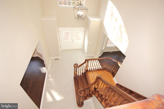 stairs with tile patterned flooring, a towering ceiling, and a chandelier