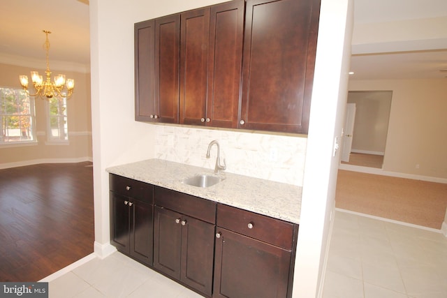 kitchen with light stone countertops, light wood-type flooring, ornamental molding, and sink