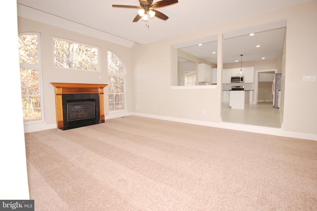 unfurnished living room featuring ceiling fan and light carpet