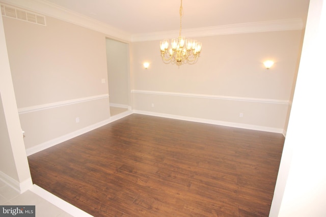 spare room featuring dark hardwood / wood-style floors, ornamental molding, and a chandelier