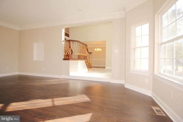 unfurnished room with dark hardwood / wood-style floors, ornamental molding, a wealth of natural light, and a chandelier