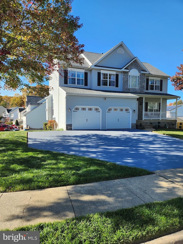 view of front of property featuring a garage, a front yard, and a porch