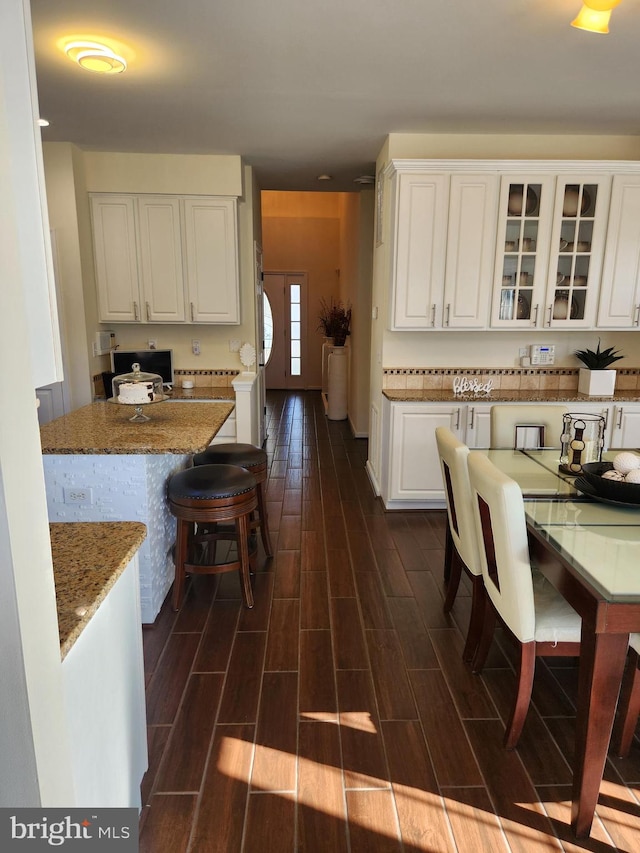 kitchen with white cabinetry, dark hardwood / wood-style floors, and light stone counters