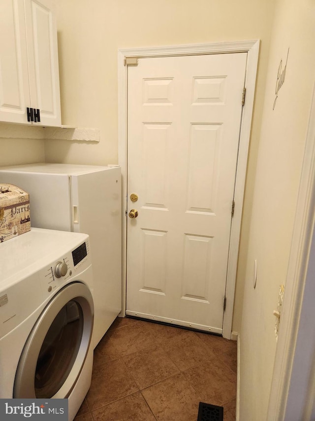 laundry room featuring dark tile patterned flooring, cabinets, and washer / dryer