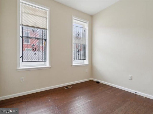 unfurnished room with a healthy amount of sunlight and dark hardwood / wood-style flooring