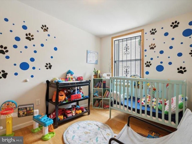 bedroom with hardwood / wood-style flooring and a nursery area