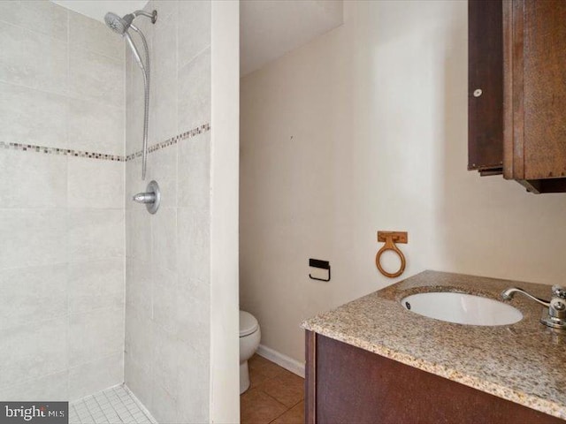 bathroom featuring vanity, tile patterned floors, toilet, and a tile shower