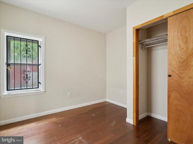 unfurnished bedroom featuring dark hardwood / wood-style flooring and a closet