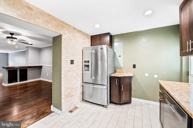 kitchen with dark brown cabinetry, light stone countertops, stainless steel appliances, and light hardwood / wood-style floors