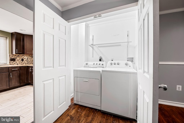 laundry room featuring washer and dryer, dark wood-type flooring, and ornamental molding