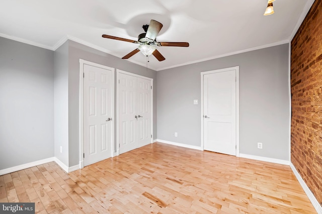 unfurnished bedroom featuring multiple closets, ceiling fan, light hardwood / wood-style flooring, brick wall, and ornamental molding