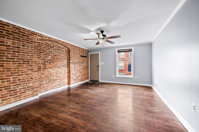 spare room with crown molding, dark hardwood / wood-style flooring, ceiling fan, and brick wall