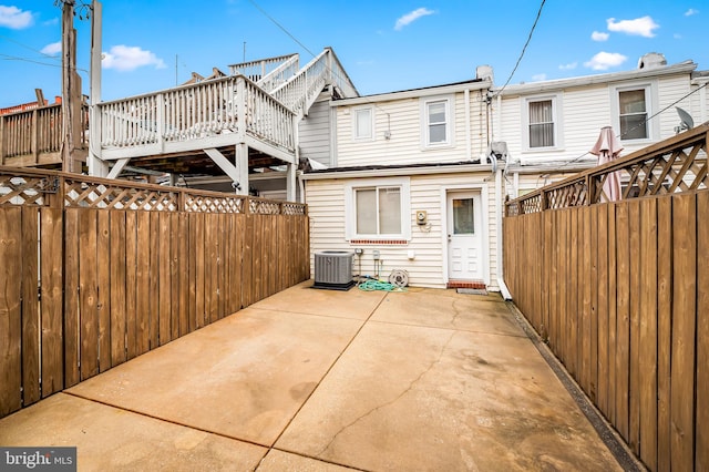 back of house with a wooden deck, a patio area, and central AC